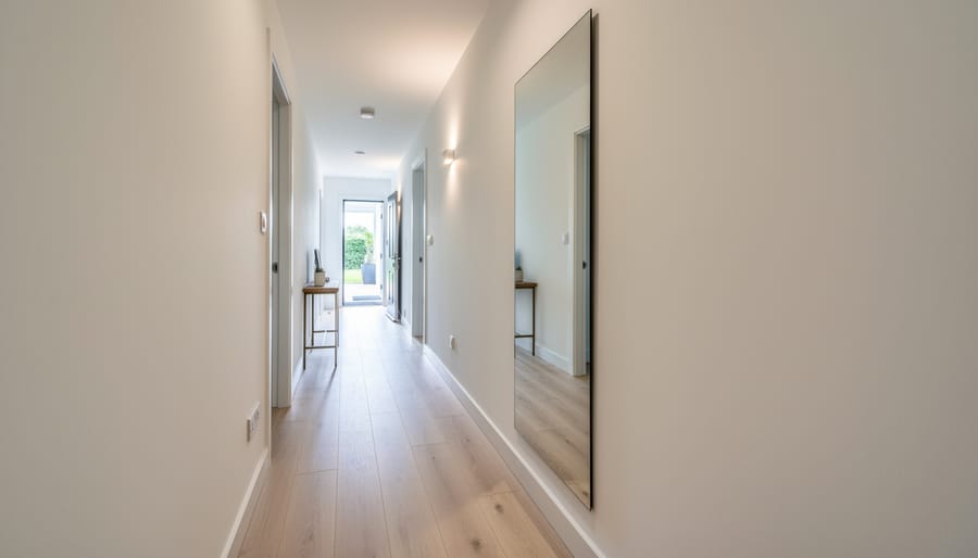 Floor-to-ceiling mirror reflecting a narrow hallway to visually expand the entry space.