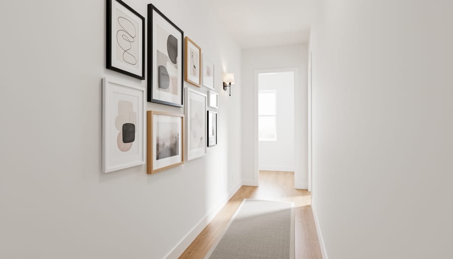 Curated framed artwork forming a gallery wall along a narrow hallway.